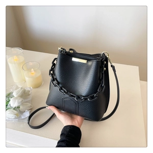 Détail d'un sac seau en cuir noir avec chaîne en résine épaisse et garnitures dorées