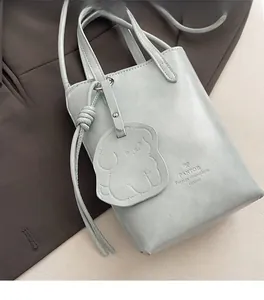 Detail of light blue bucket bag showing textured leather finish and silver hardware