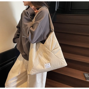 Close-up of cream textured hobo bag with unique pleated fabric and square woven label