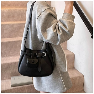 Detail of black pebbled leather hobo bag with adjustable strap and mini coin pouch accessory