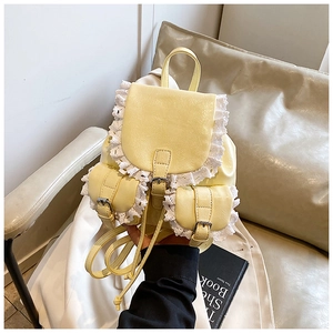 Detail of light yellow PU leather backpack featuring delicate white lace trim and straps