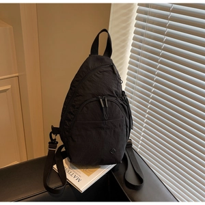 Close-up of a black waterproof nylon mini backpack with multiple zipper pockets on a table