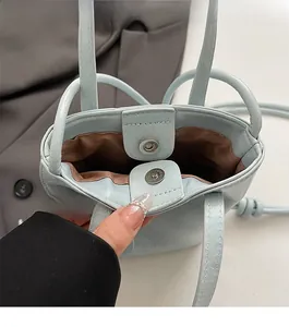 Detail view of mini light blue leather bucket bag with magnetic closure and brown lining