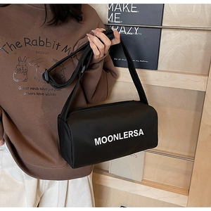 Detail of black canvas pillow bag with wide shoulder strap and white logo