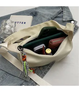 Detail view of the spacious inner compartment of the cream nylon dumpling crossbody bag