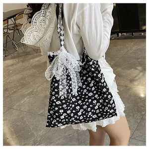 Détail du sac cabas en toile à fleurs avec nœud en dentelle blanche et bordure de sangle