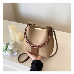 Vue détaillée du sac seau beige en cuir grainé avec une chaîne marron élégante et sangle