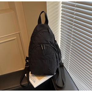 Detail of black nylon crossbody bag with multi-zipper pockets and metal logo patch