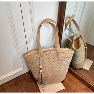 Detail of straw woven tote bag with lace hollow pattern and beaded tassel decor