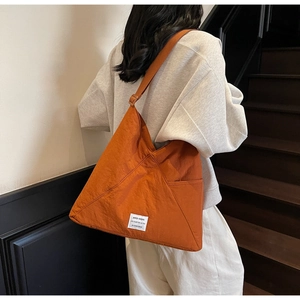 Close-up of orange large capacity crossbody bag with textured fabric and wide strap