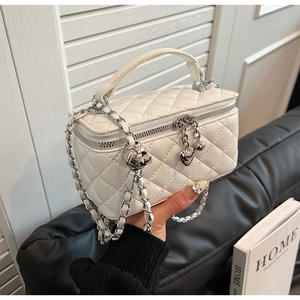 Detailed close-up of quilted white leather box bag with silver chain and heart charm