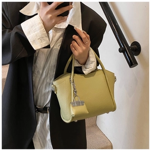 Detailed lime green lychee leather bucket bag with a mini charm pouch and metal hardware