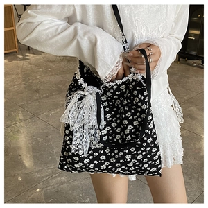 Détail du sac cabas en toile fleurie noire avec nœud en dentelle blanche et bandoulière