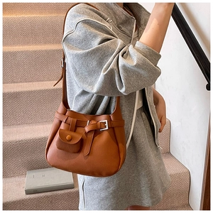 Close-up of brown lychee grain leather shoulder bag with silver belt buckle and side pouch