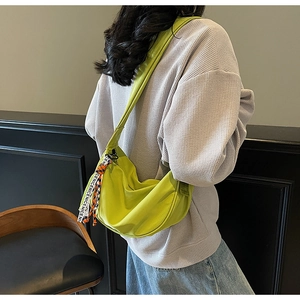 Detail of lime green half-moon crossbody bag featuring textured fabric and a decorative strap