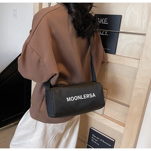 Detail of black cylindrical crossbody bag with white MOONLERSA lettering and wide strap