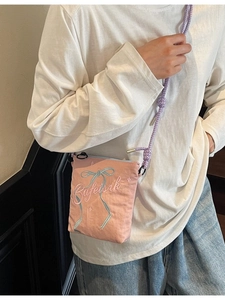 Pink canvas bucket bag with blue bow embroidery and purple rope shoulder strap