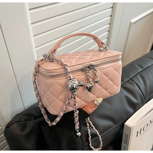 Detail view of pink quilted handbag with gold chain strap and heart charm accents