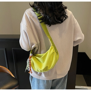 Macro shot of the bright green crescent bag showing the adjustable strap and orange woven tag