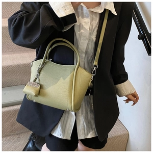 Detail view of grass green lychee leather bucket bag with mini purse charm and shoulder strap
