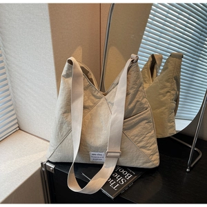 Detail of beige nylon tote bag with pleated texture and stylish fabric label on desk