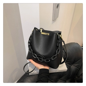 Détail du sac seau noir en cuir grainé avec chaîne épaisse et finitions dorées