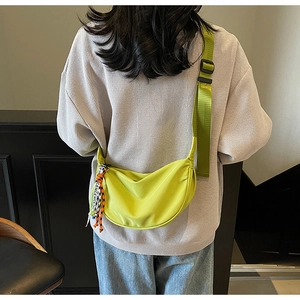 Detail of neon green nylon crescent bag featuring adjustable strap and woven brand tag