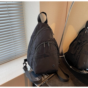 Detail of minimalist black nylon backpack with multi-zipper compartments and metallic logo