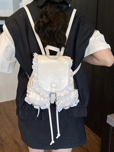 White bucket backpack with lace trim and metallic buckles shown on model