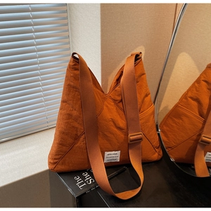Detail of caramel oversized tote bag featuring crinkled texture and adjustable strap