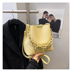 Détail du sac seau jaune clair avec texture cuir grainé et poignée en chaîne chic