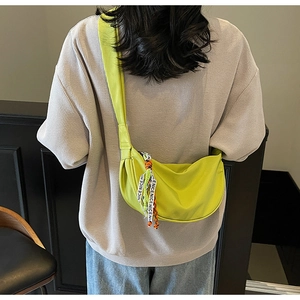 Detail of neon green half-moon crossbody bag featuring decorative NICE ribbon strap