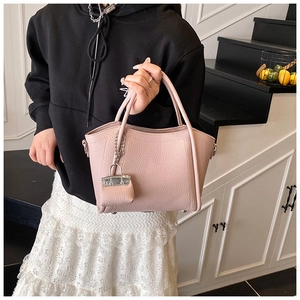 Detailed shot of pink lychee leather handbag with a matching mini bag charm accessory