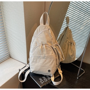 Detail view of a cream water-drop teardrop backpack with multiple zip pockets and drawstrings