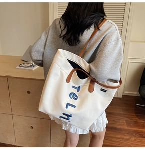 Sac fourre-tout minimaliste en toile avec anses en cuir porté par un mannequin