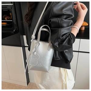 Mini silver metallic tote bag with bear charm shown in a modern lifestyle setting