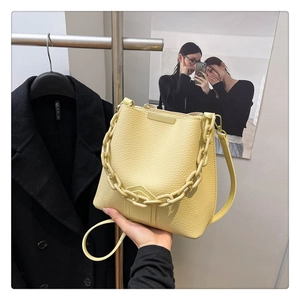 Détail du sac seau en cuir jaune clair à motif litchi avec une grosse chaîne