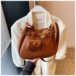 Detailed close-up of brown litchi pattern shoulder bag with decorative buckle and mini pouch