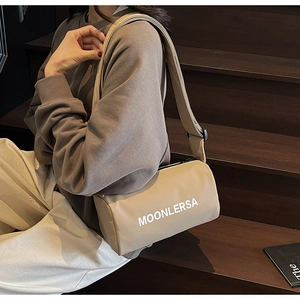 Detail of canvas pillow bag with wide strap and Moonlersa logo on a wooden staircase