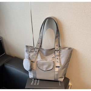 Detail of silver nylon tote bag showing adjustable eyelet straps and round coin purse
