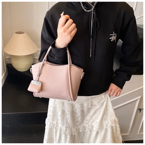 Detail of pink lychee leather bucket bag with mini purse charm and sturdy handle
