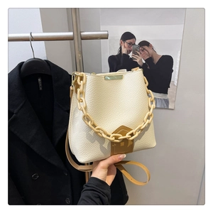 Détail du sac seau en cuir grainé blanc cassé avec chaîne en résine et bandoulière brune