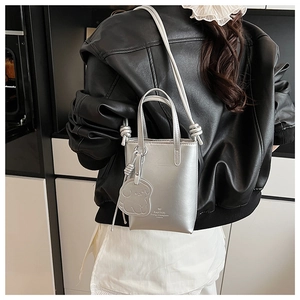 Silver mini bucket bag with adjustable strap and puppy charm shown on a model