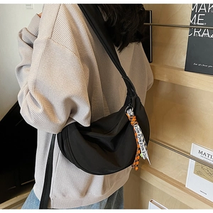 Detail of a black nylon crescent crossbody bag featuring a branded decorative lanyard