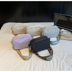 Detailed view of five colorful canvas camera bags with wide branded jacquard straps
