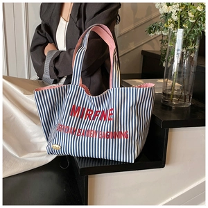 Detail of blue striped canvas tote with red lettering and pink lining interior