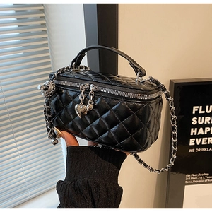 Detail of black quilted chain bag featuring silver heart zipper and metallic charm
