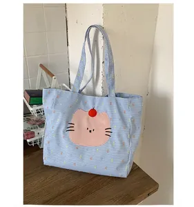 Détail du cabas à carreaux bleus avec écusson chat rose et intérieur spacieux en toile robuste