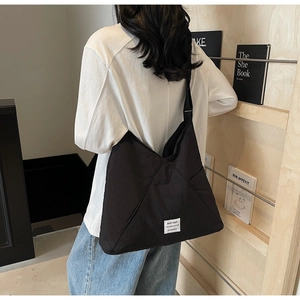 Close-up of black canvas crossbody bag side pocket and white decorative label detail