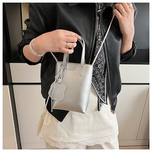 Close-up of metallic silver mini bucket bag with cartoon dog charm and shoulder strap